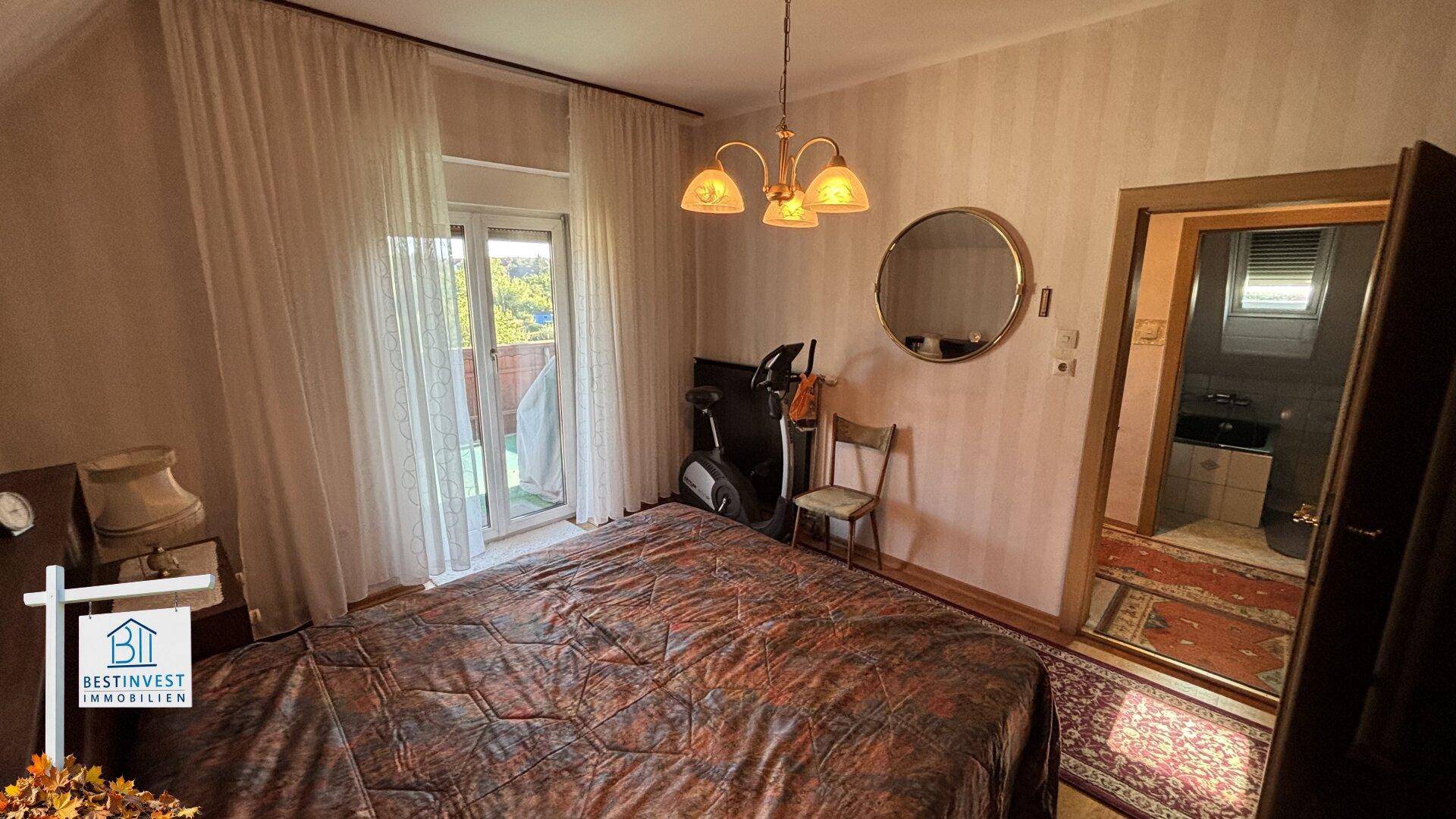 Schlafzimmer mit Doppelbett, Balkonzugang und Blick ins Grüne.