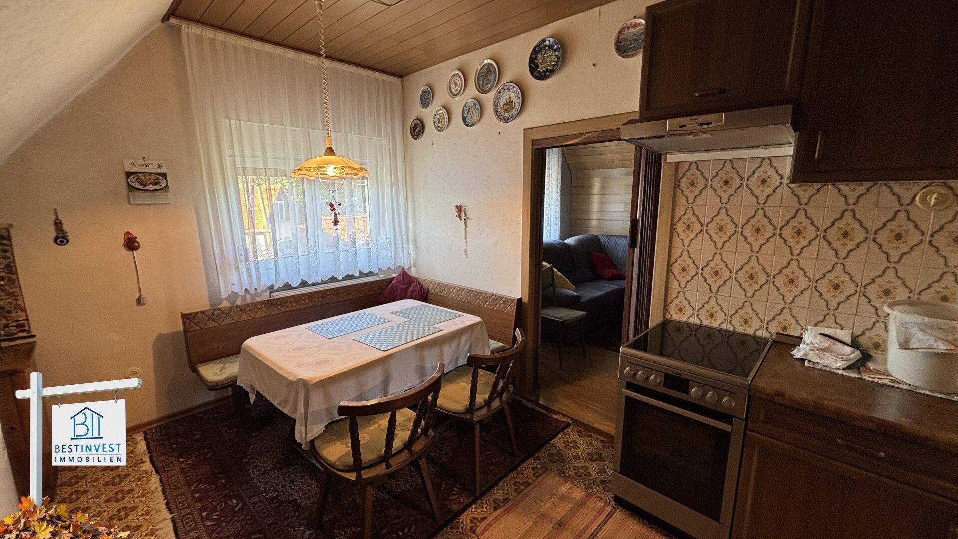 Gemütliche Dachgeschossküche mit Essbereich, traditionellen Fliesen und Blick ins Nebenzimmer.