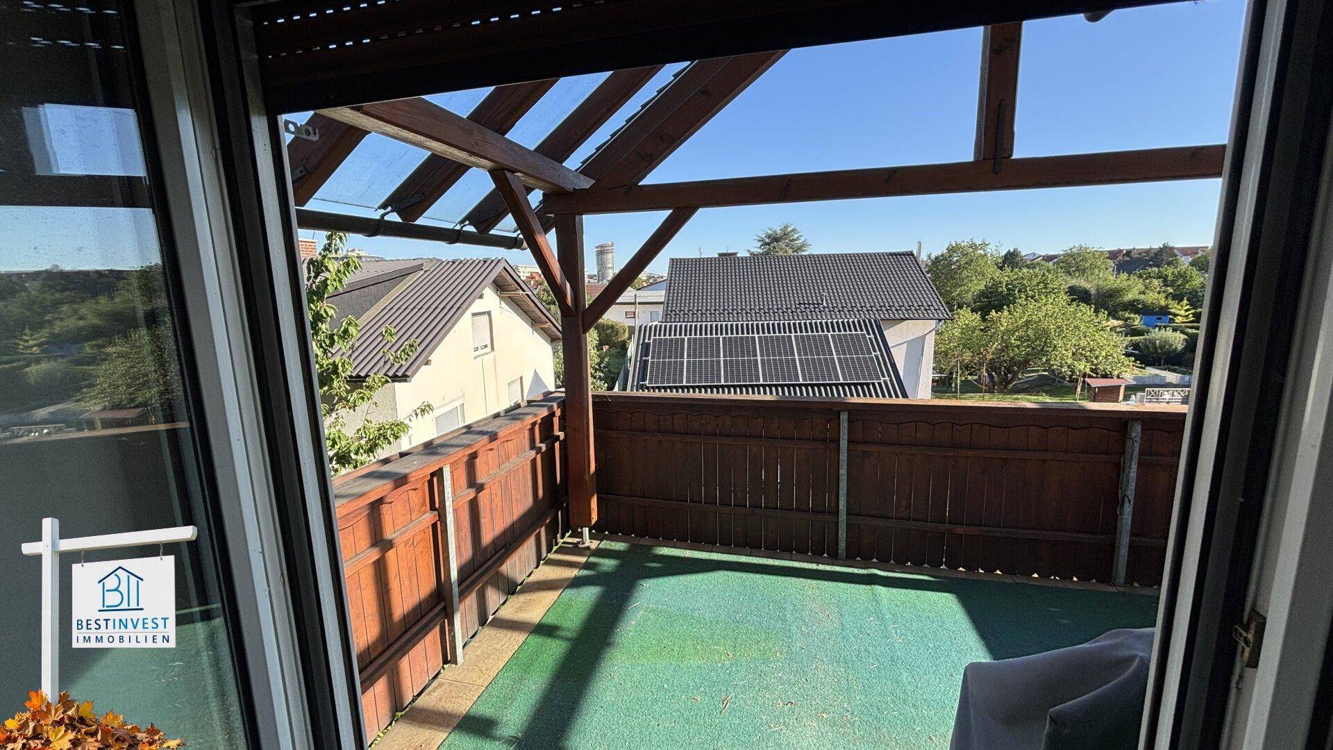 Terrasse mit Holzpergola und Ausblick auf die Umgebung mit Solaranlagen.