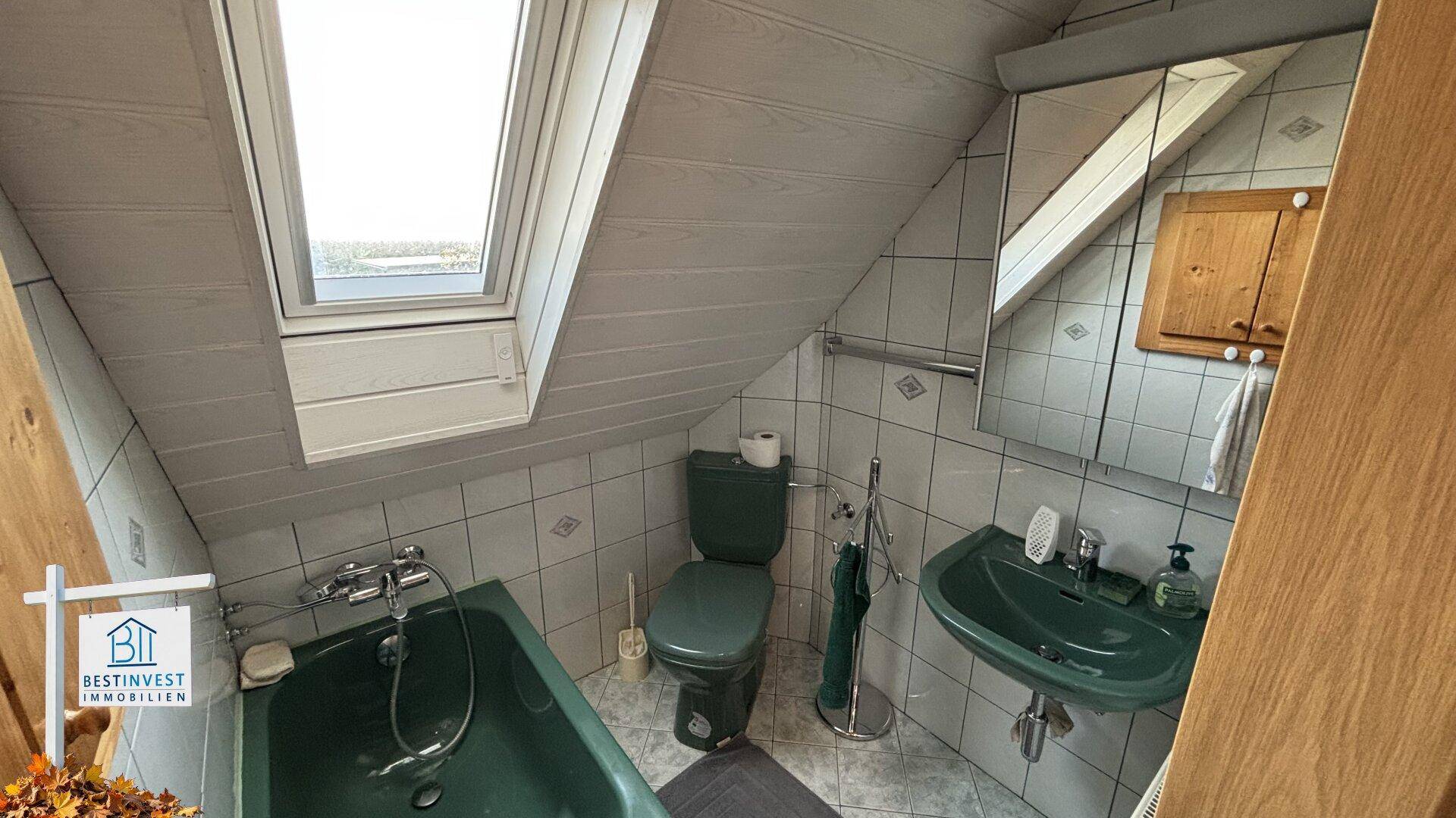 Badezimmer im Dachgeschoss mit Badewanne, WC, Waschbecken und Dachfenster.