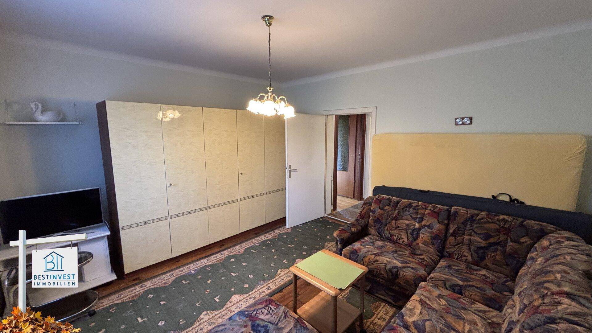 Raum mit großem Kleiderschrank, Sofa und Teppichboden, bietet viel Stauraum.