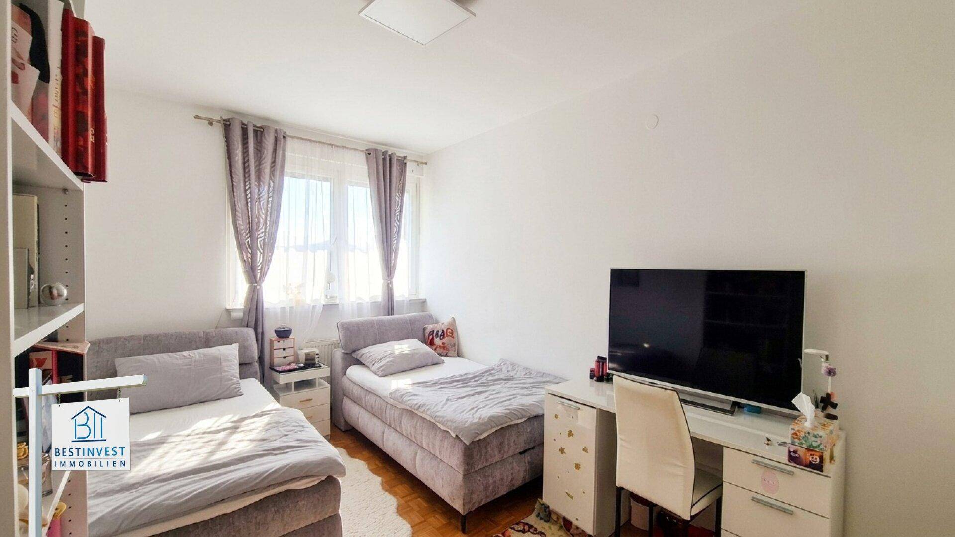 Kinder- oder Gästezimmer mit zwei Einzelbetten, Schreibtisch und hellem Parkettboden.