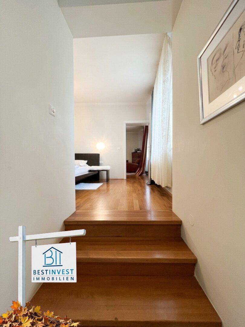 Heller Flur mit Holztreppe, die zu einem Schlafzimmer im oberen Bereich führt.