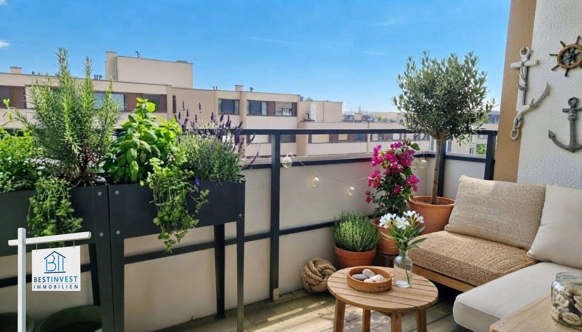 Gemütlicher Balkon mit Pflanzen, Sitzgelegenheiten und Blick auf die umliegenden Gebäude.