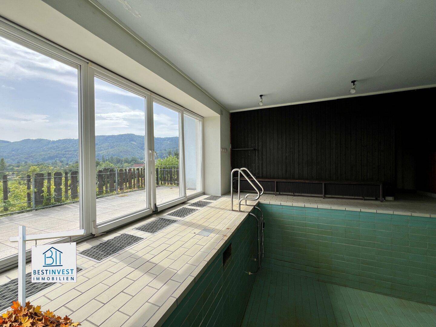 Innenpoolbereich mit großen Panoramafenstern und Blick auf die Landschaft.