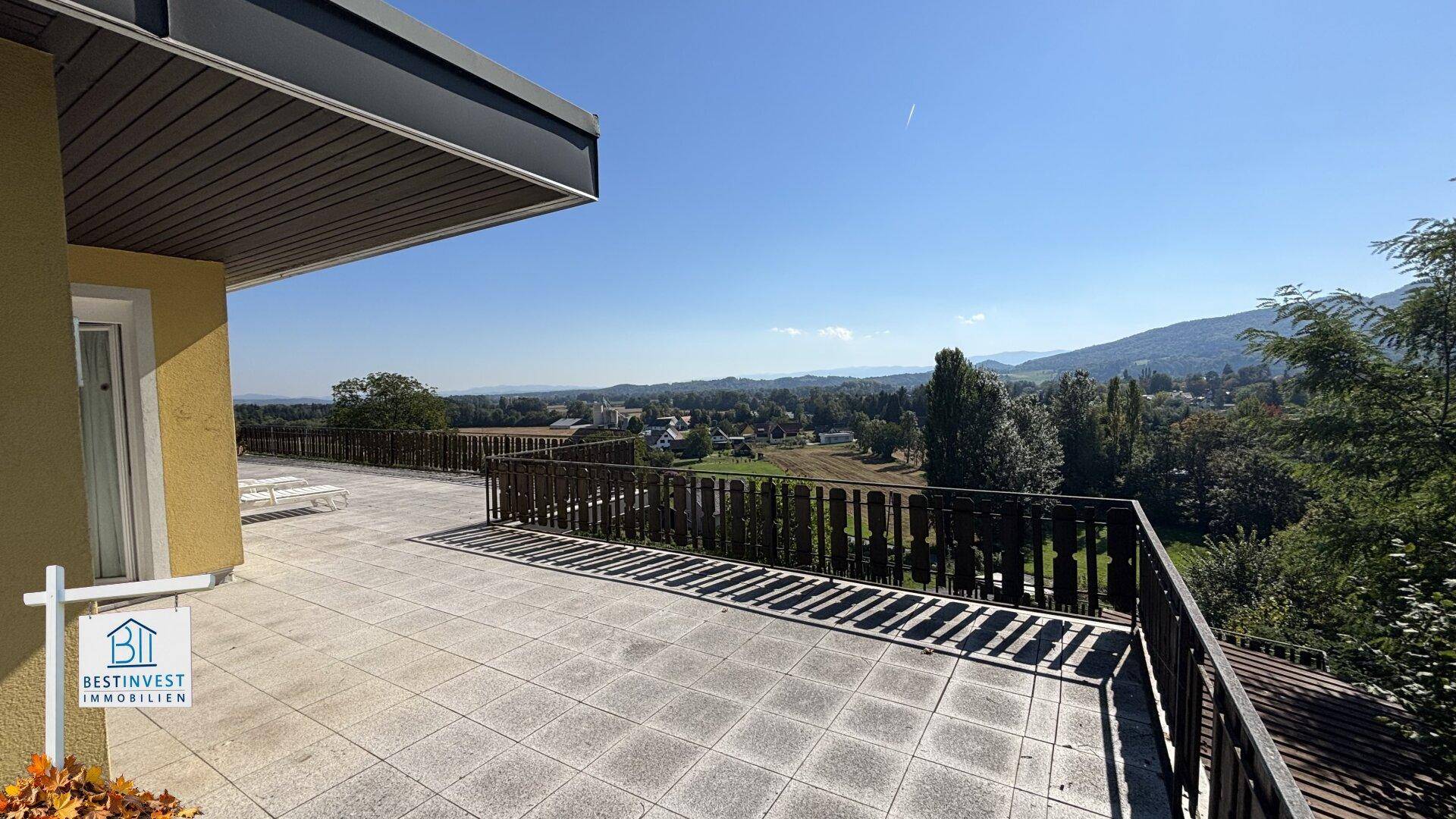 Geräumige Terrasse mit Fliesenboden und weitem Blick in die grüne Umgebung.