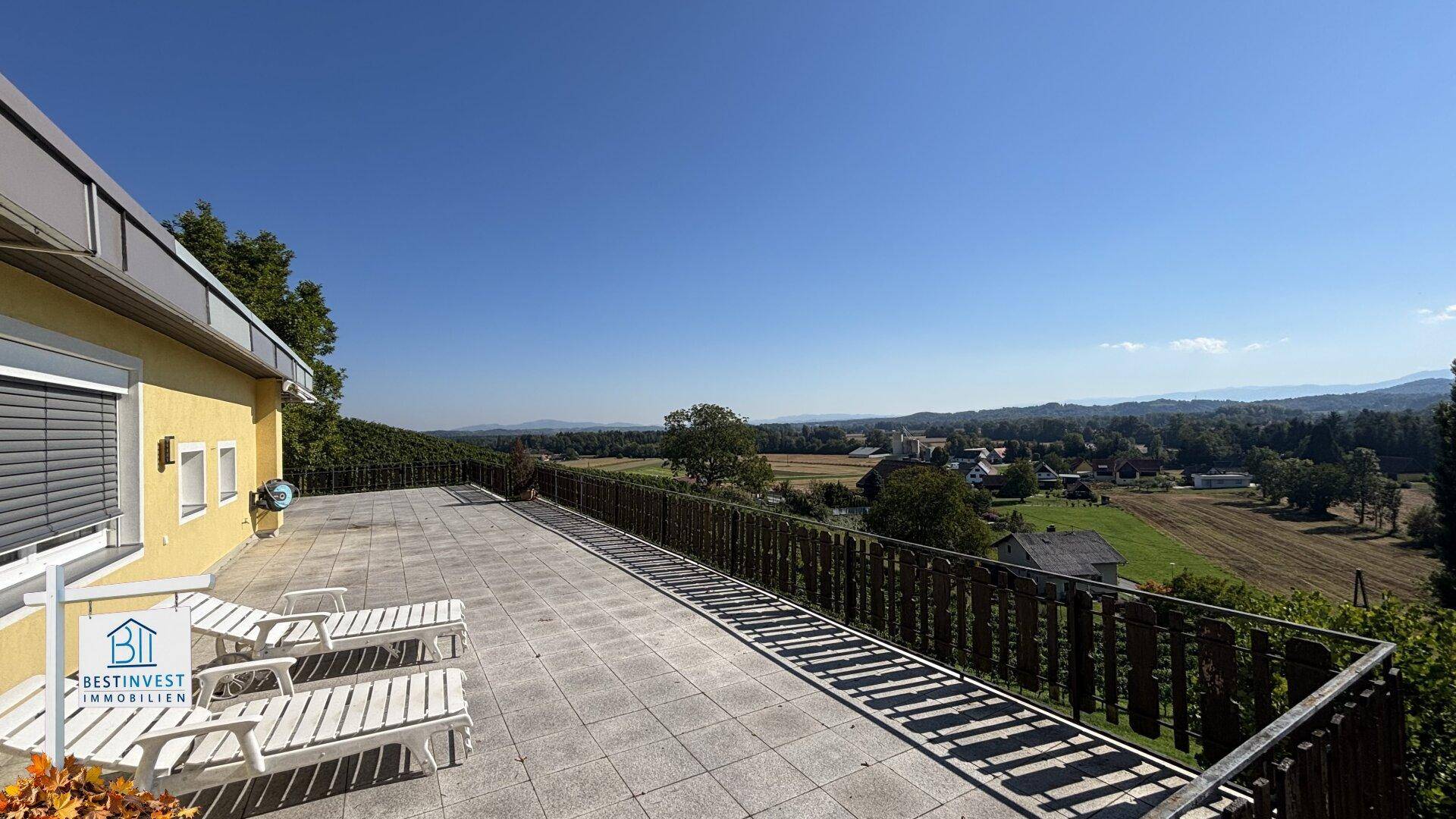 Weitläufige Terrasse mit Liegestühlen und Panoramablick über die Landschaft.