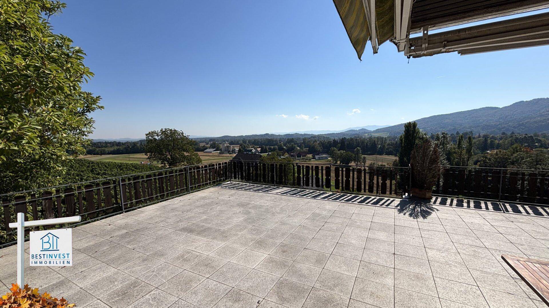 Große geflieste Terrasse mit Markise und beeindruckendem Weitblick über die Landschaft.