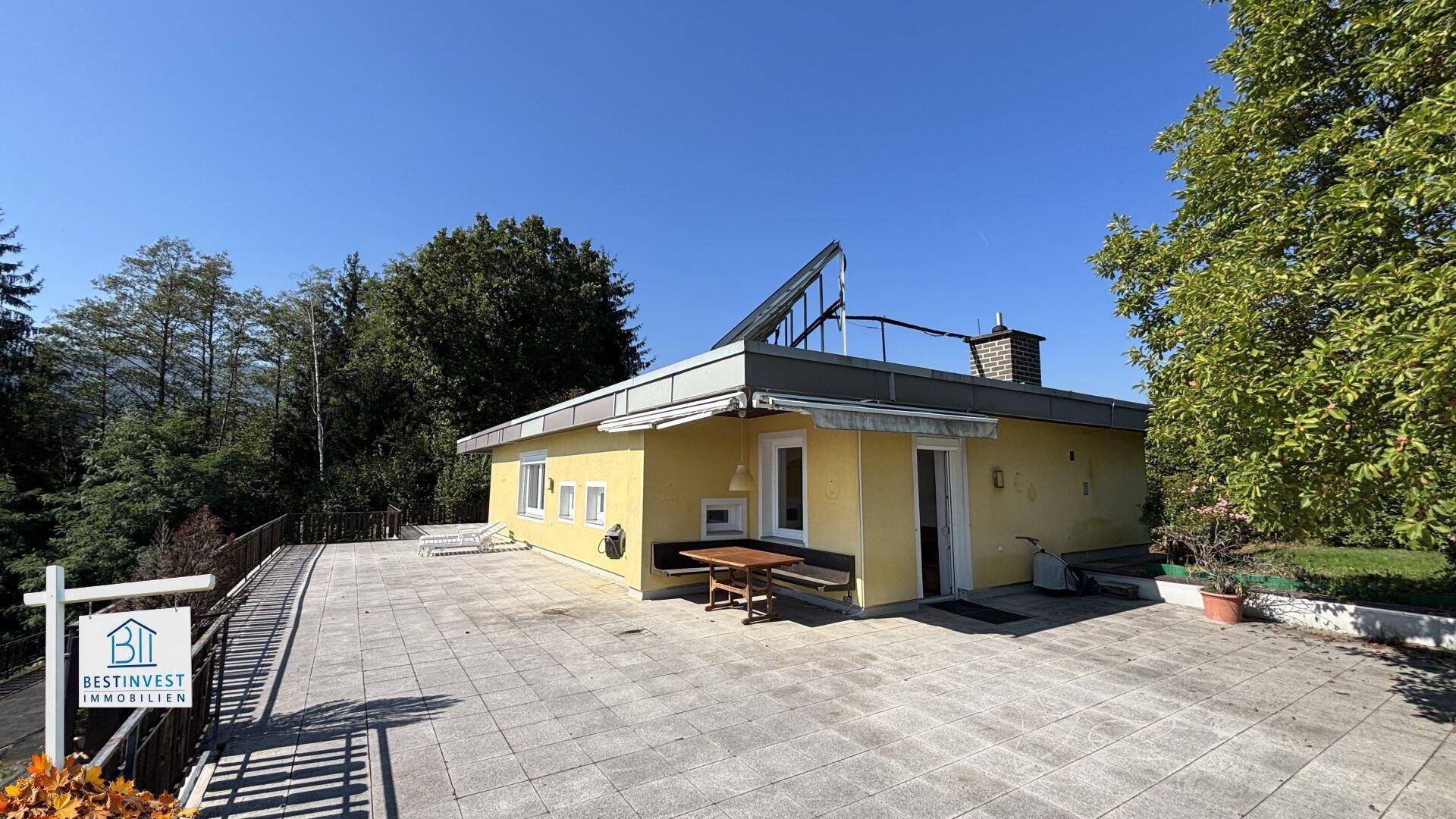 Große geflieste Terrasse am Haus mit Blick auf die umliegende Landschaft.