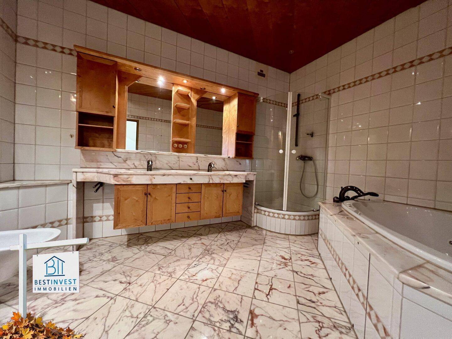 Geräumiges Badezimmer mit Marmorfliesen, Doppelwaschbecken, Dusche und Eckbadewanne.