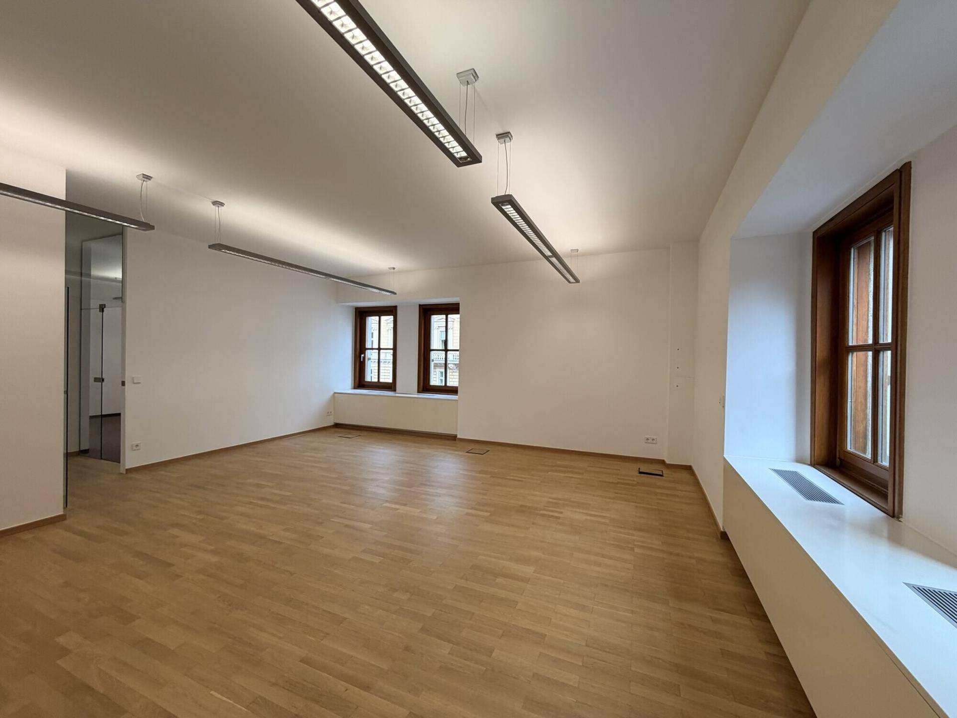Großes, leeres Büro mit Holzparkett und hohen Decken, bereit für die individuelle Gestaltung.