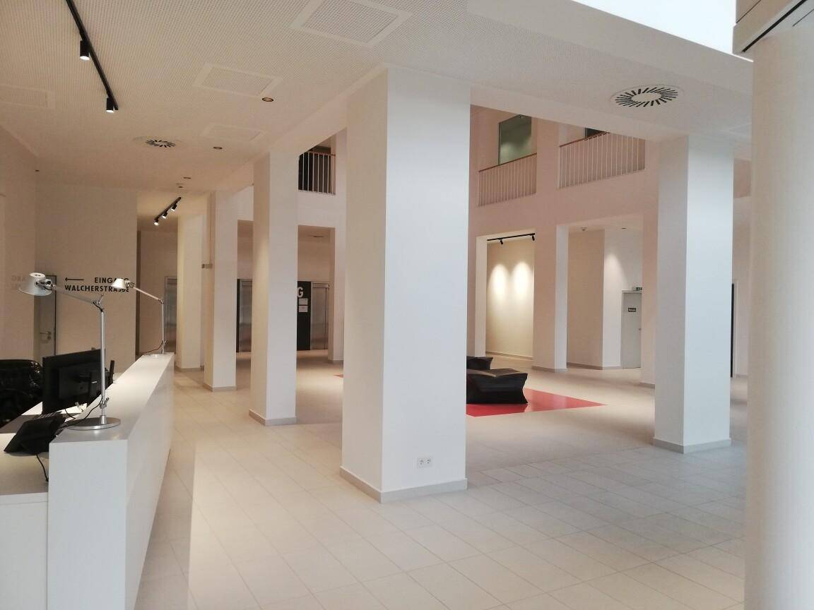 Empfangsbereich mit moderner Rezeption, hohen Säulen und Blick auf die stilvolle Sitzecke der Lobby.