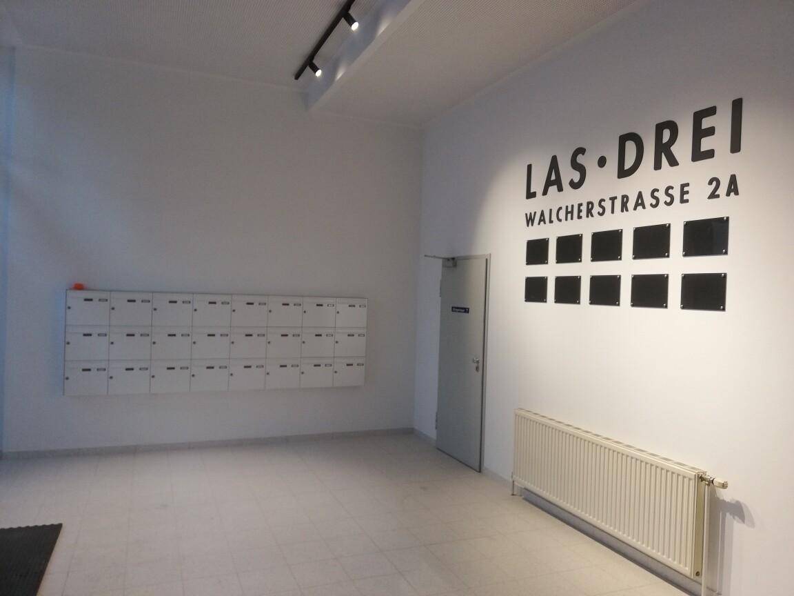 Heller Postraum oder Eingangsbereich mit zahlreichen Briefkästen und einem Heizkörper an der Wand.
