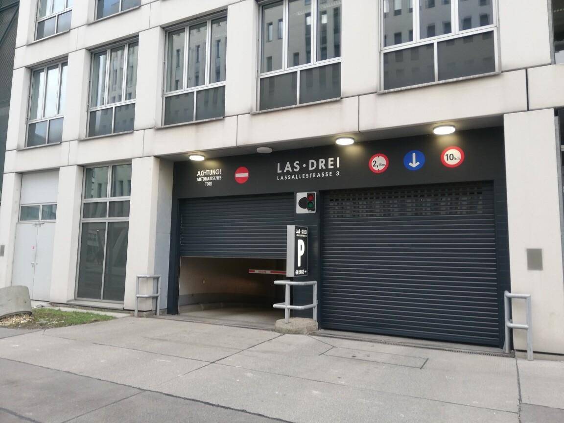 Einfahrt zur Tiefgarage mit geöffnetem Rolltor, Verkehrsschildern und Ampelanlage.