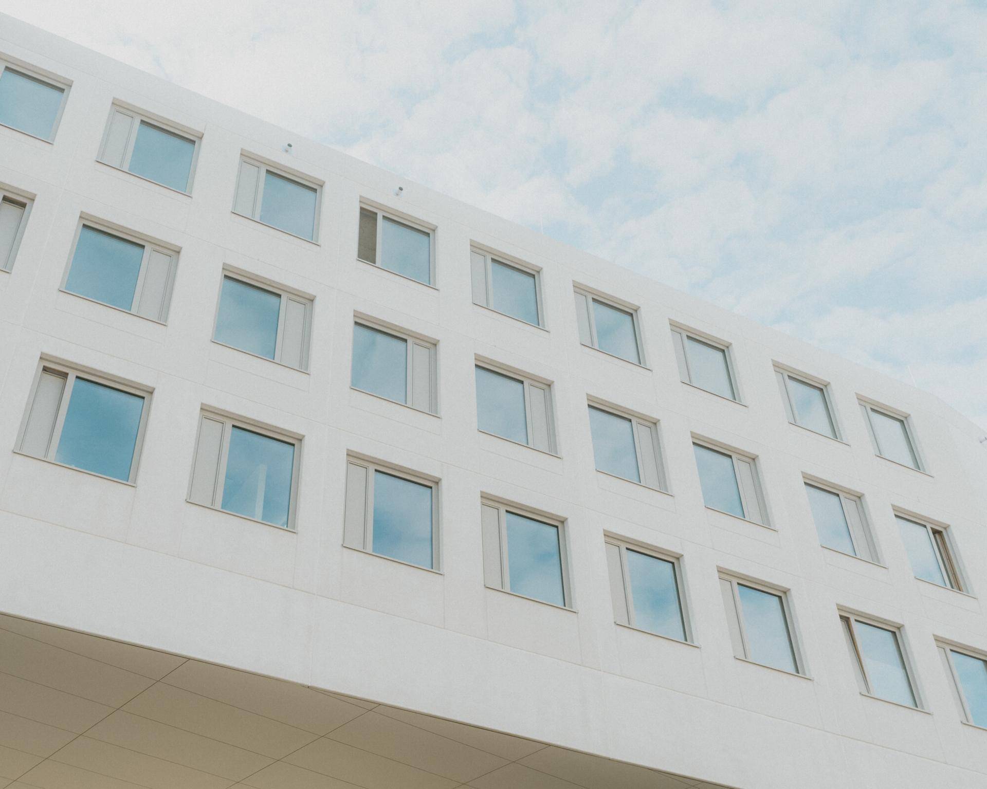 Moderne Gebäudefassade mit zahlreichen quadratischen Fenstern und einer klaren, weißen Architektur.