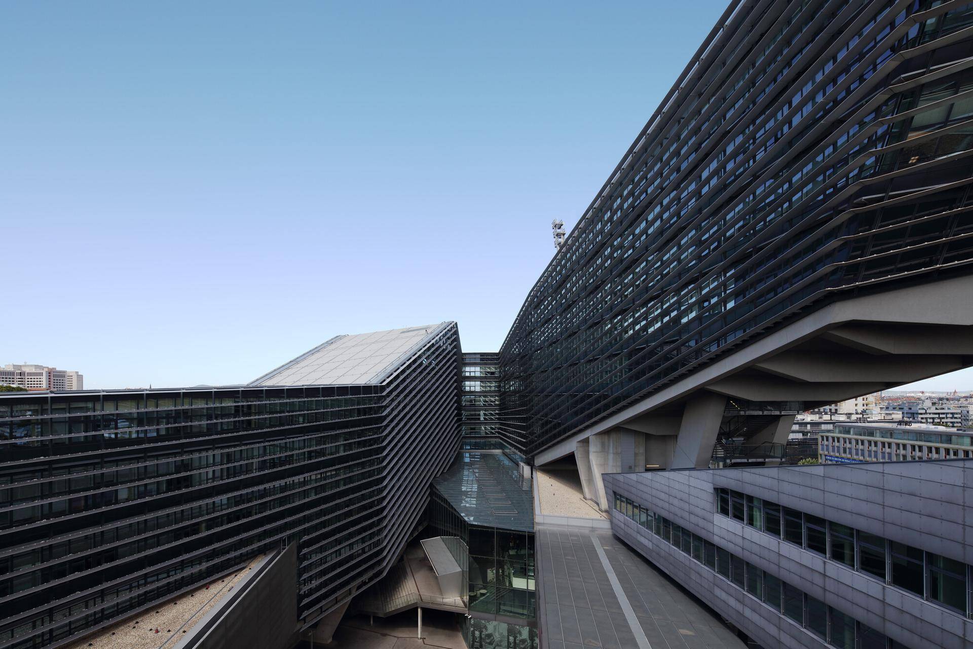 Architektonisch komplexes Gebäudeensemble mit mehreren Flügeln und Glasfassaden unter blauem Himmel.
