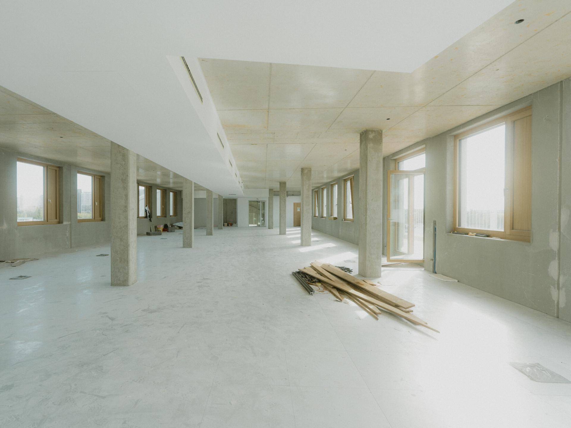 Heller, offener Büroraum im Rohbau mit vielen Fenstern und Betonpfeilern, bereit für den Ausbau.
