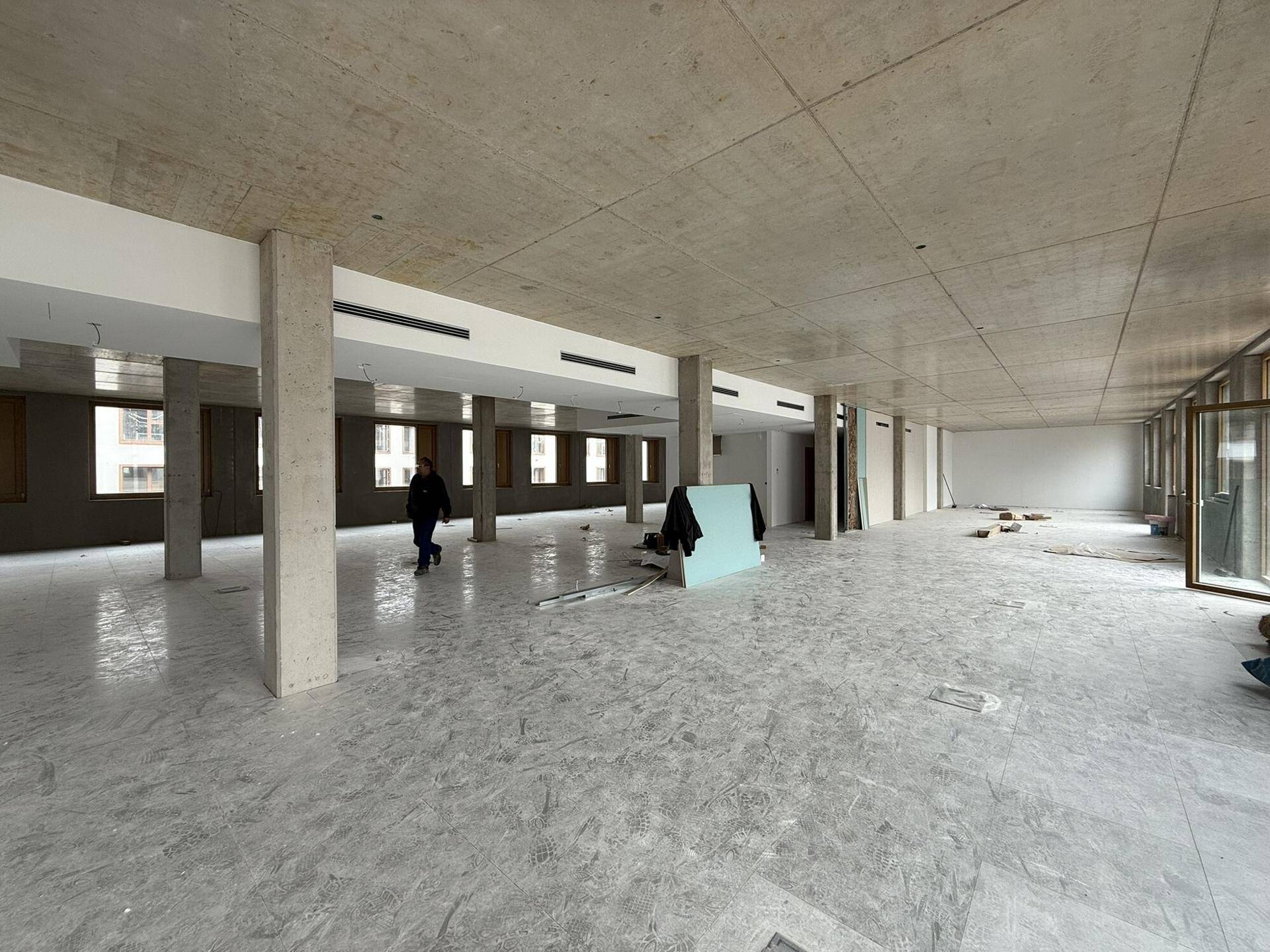 Weitläufiger Bürobereich im Rohbau mit Sichtbetondecke und Säulen, bereit für den Innenausbau.
