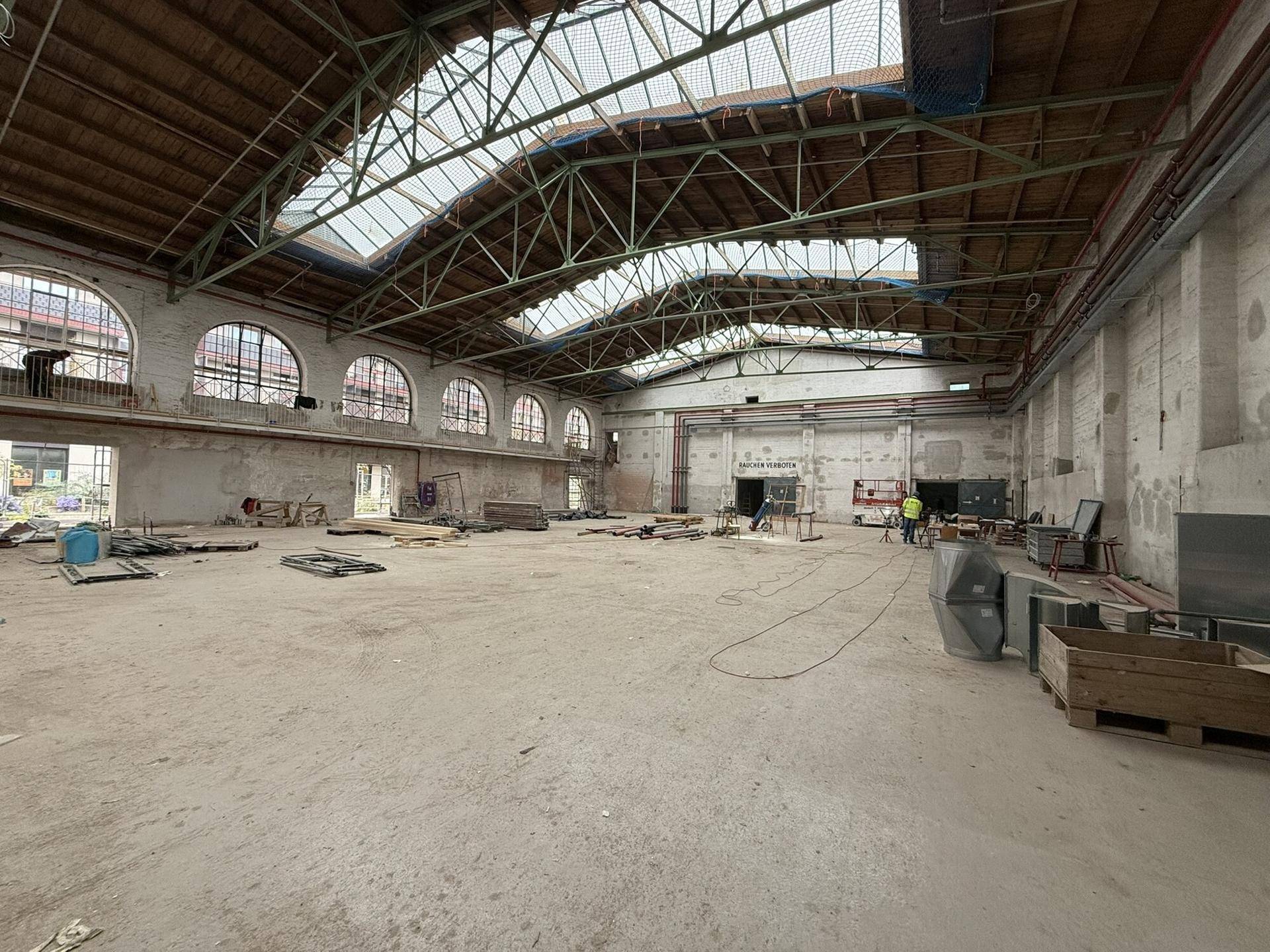 Weitläufige Industriehalle mit gewölbter Dachkonstruktion, Oberlichtern und viel Tageslicht.