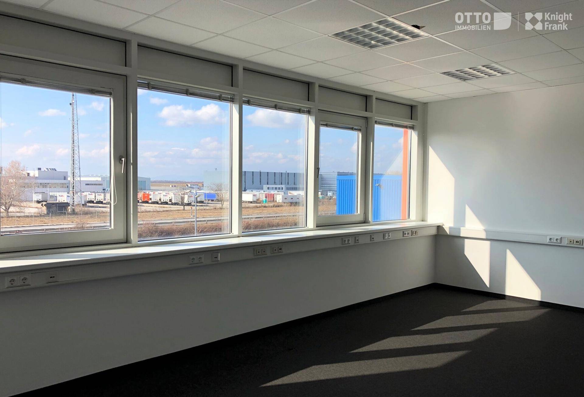 Helles Büro mit großen Fenstern und Blick auf das Industriegelände.
