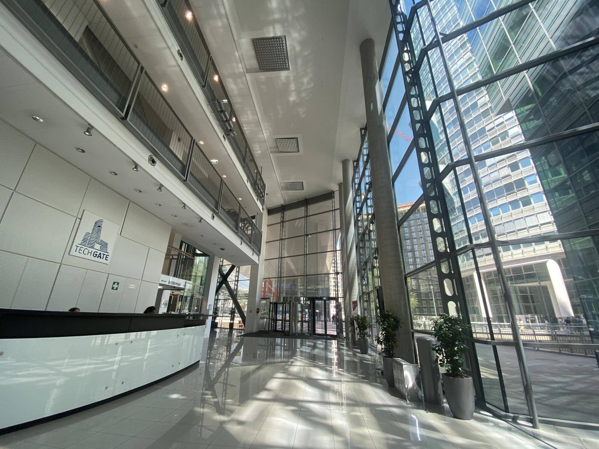 Moderne Empfangshalle mit Rezeption, hohen Decken und großen Glasflächen in einem Bürogebäude.
