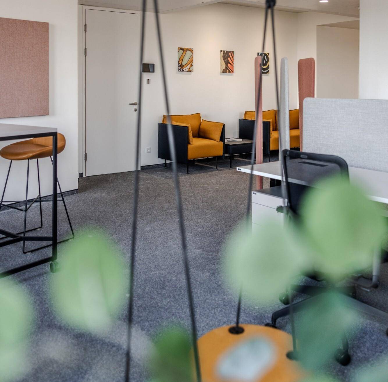 Gemütlicher Loungebereich in einem Büro mit bequemen Sesseln und Teppichboden, ideal für Pausen.