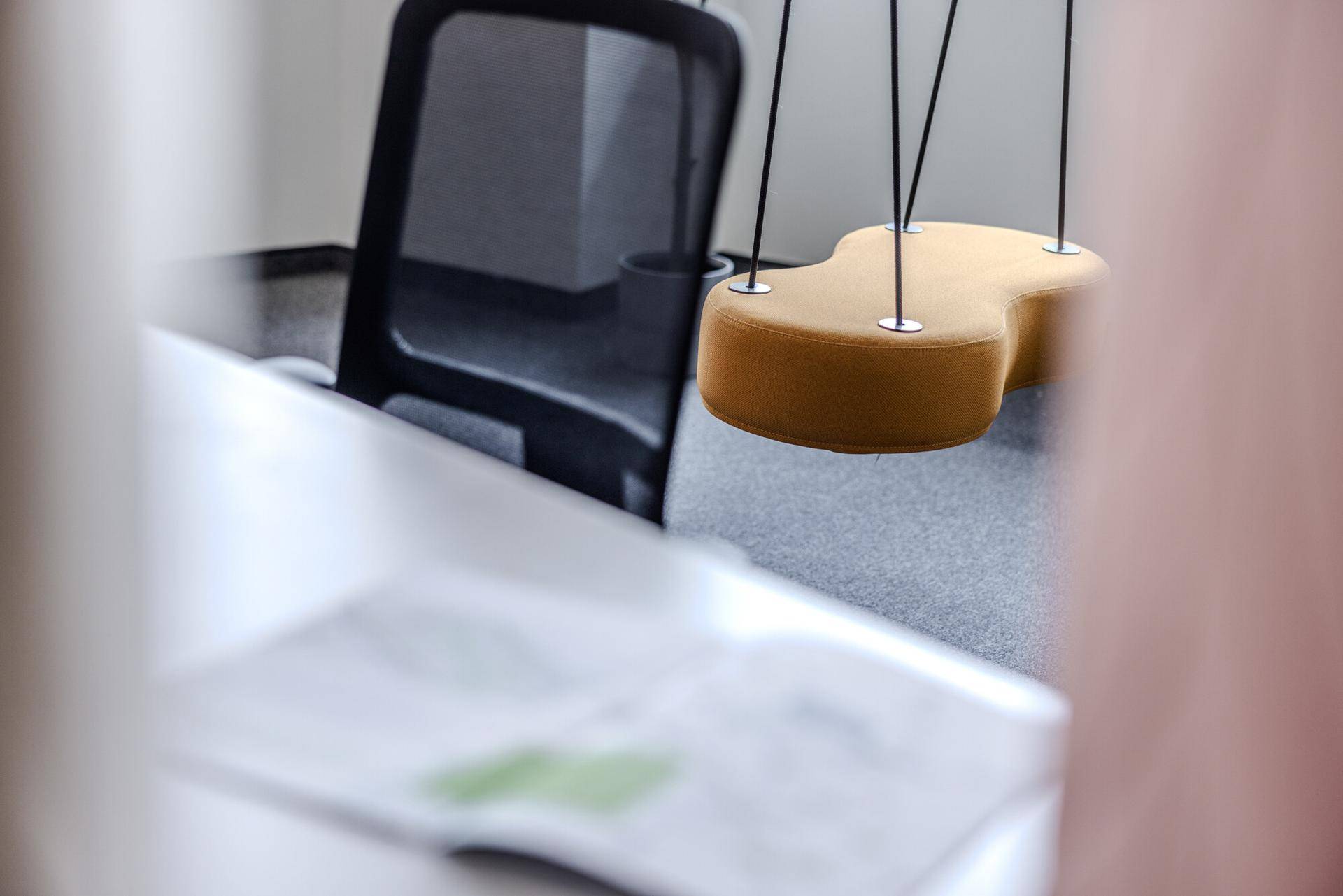 Detailaufnahme eines modernen Büros mit ergonomischem Stuhl und einer dekorativen Hängeschaukel als Akzent.