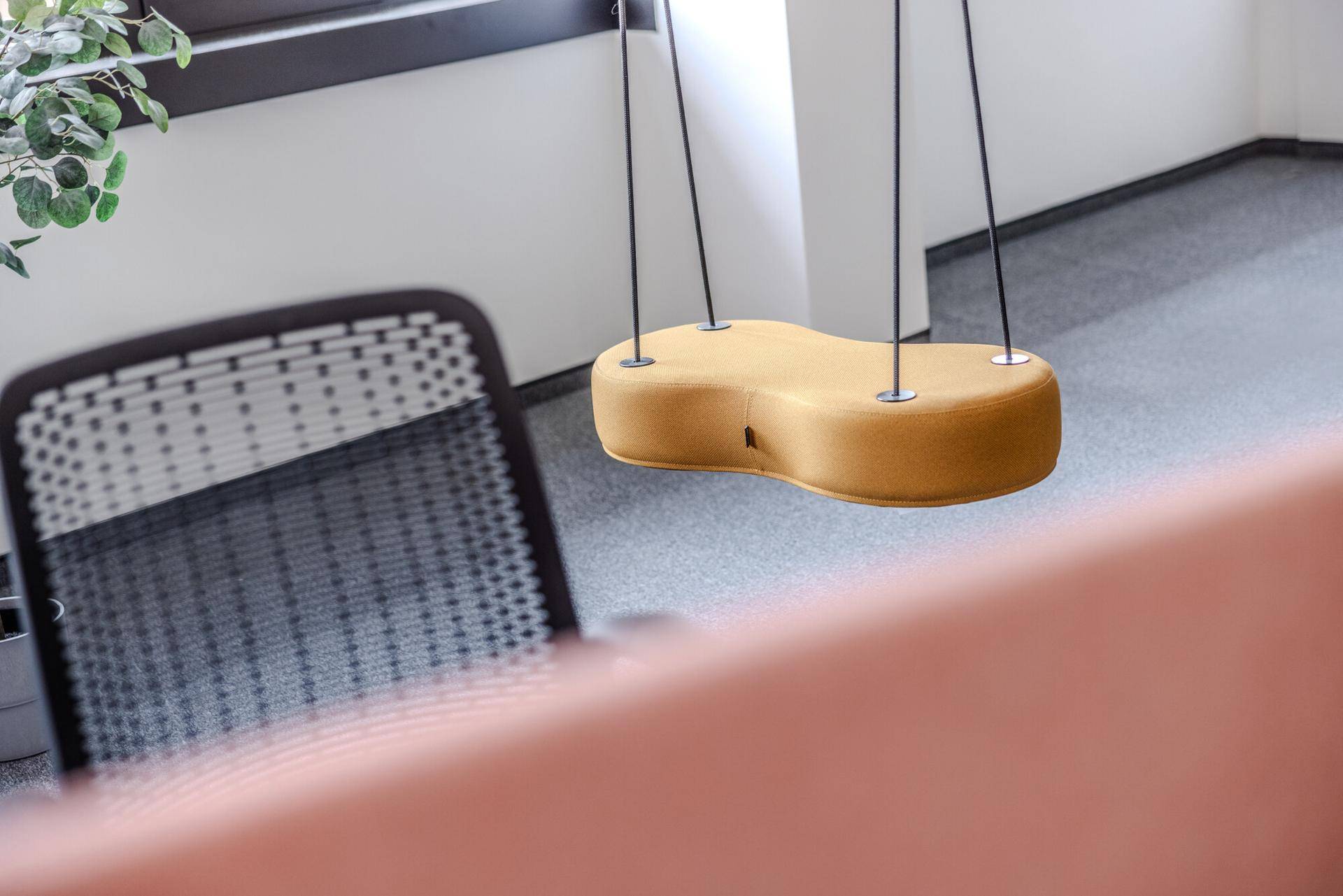 Detailaufnahme eines modernen Schaukelstuhls in einem hellen Bürobereich mit Teppichboden, der zum Entspannen einlädt.
