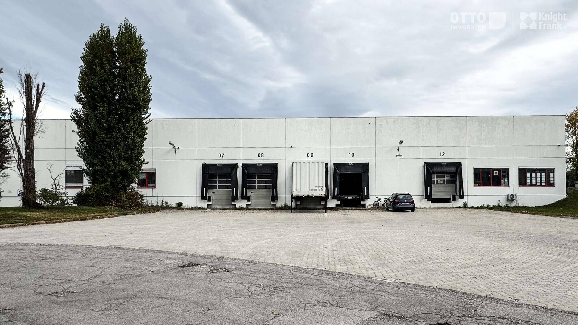 Außenansicht einer Lagerhalle mit mehreren Laderampen und einem großen Vorplatz.