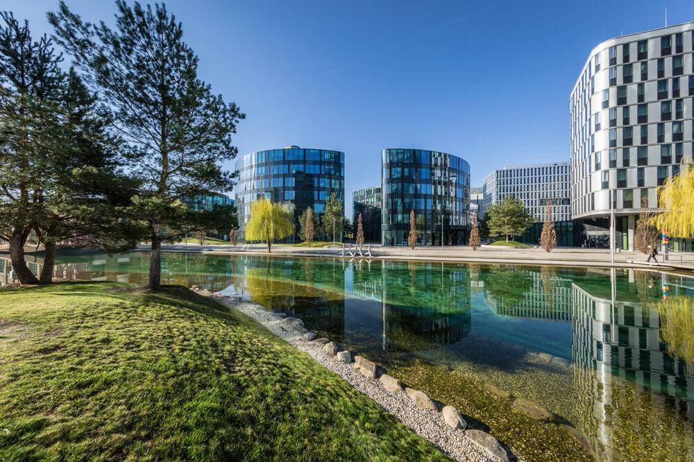 Panoramablick auf die modernen Bürokomplexe mit ihren reflektierenden Glasfassaden und der weitläufigen Grünanlage.