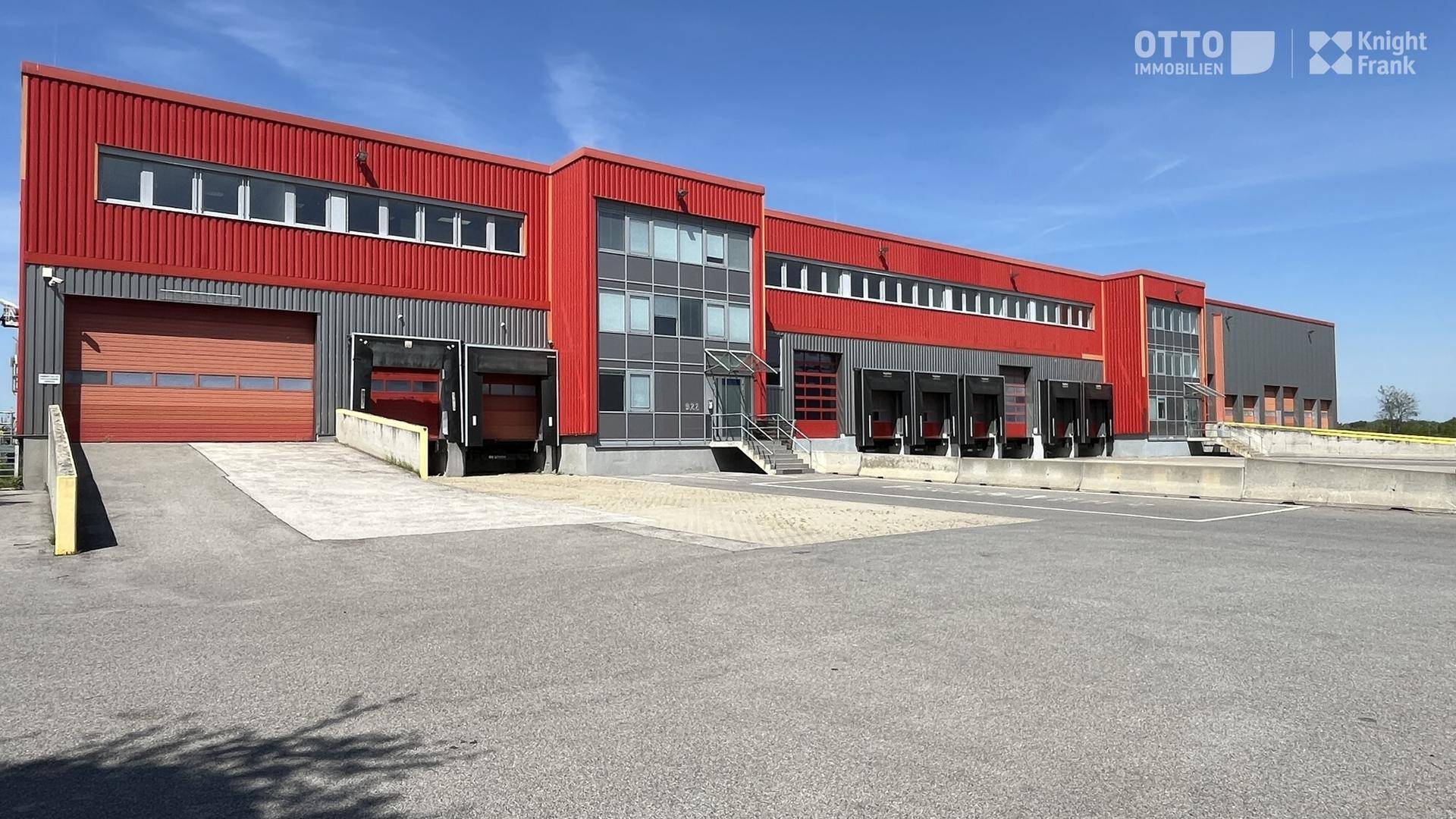 Detailansicht des Industriegebäudes mit roten Fassaden und mehreren Laderampen für LKWs.