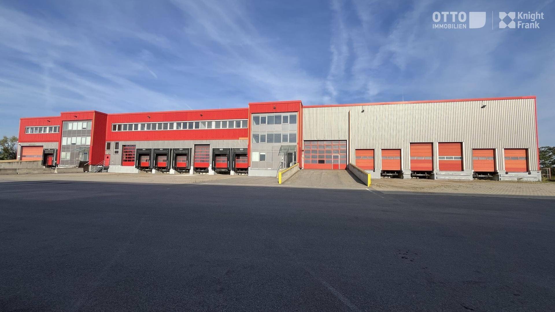 Weitläufiges Industrie- und Logistikgebäude mit roter Fassade und vielen Rolltoren für Anlieferungen.