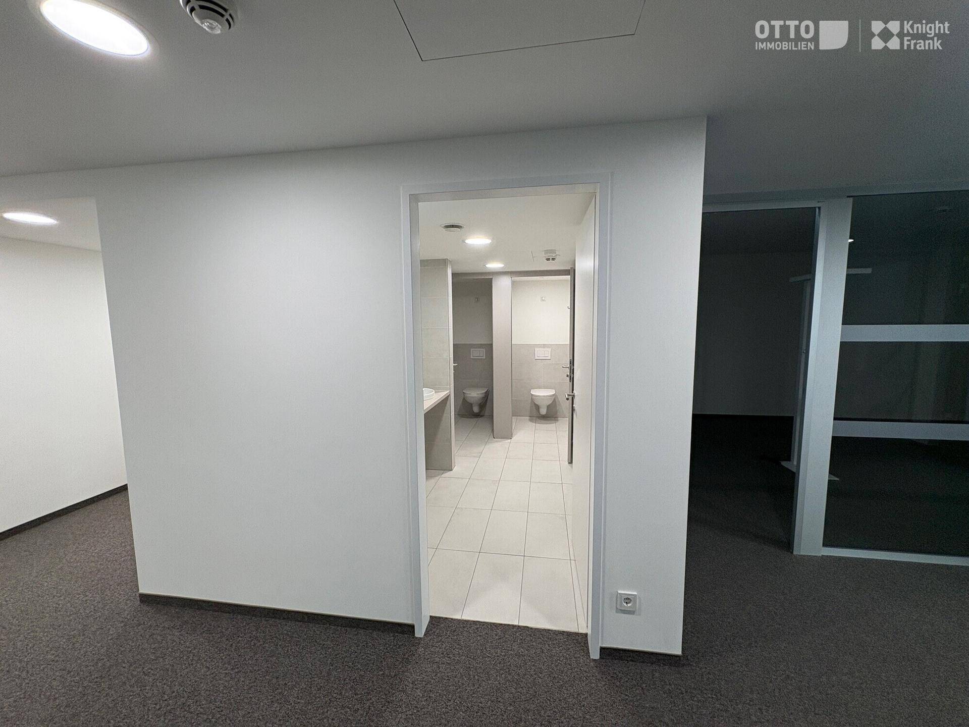 Flur mit Zugang zu den Toiletten, gekennzeichnet durch helle Fliesen und saubere Wände.