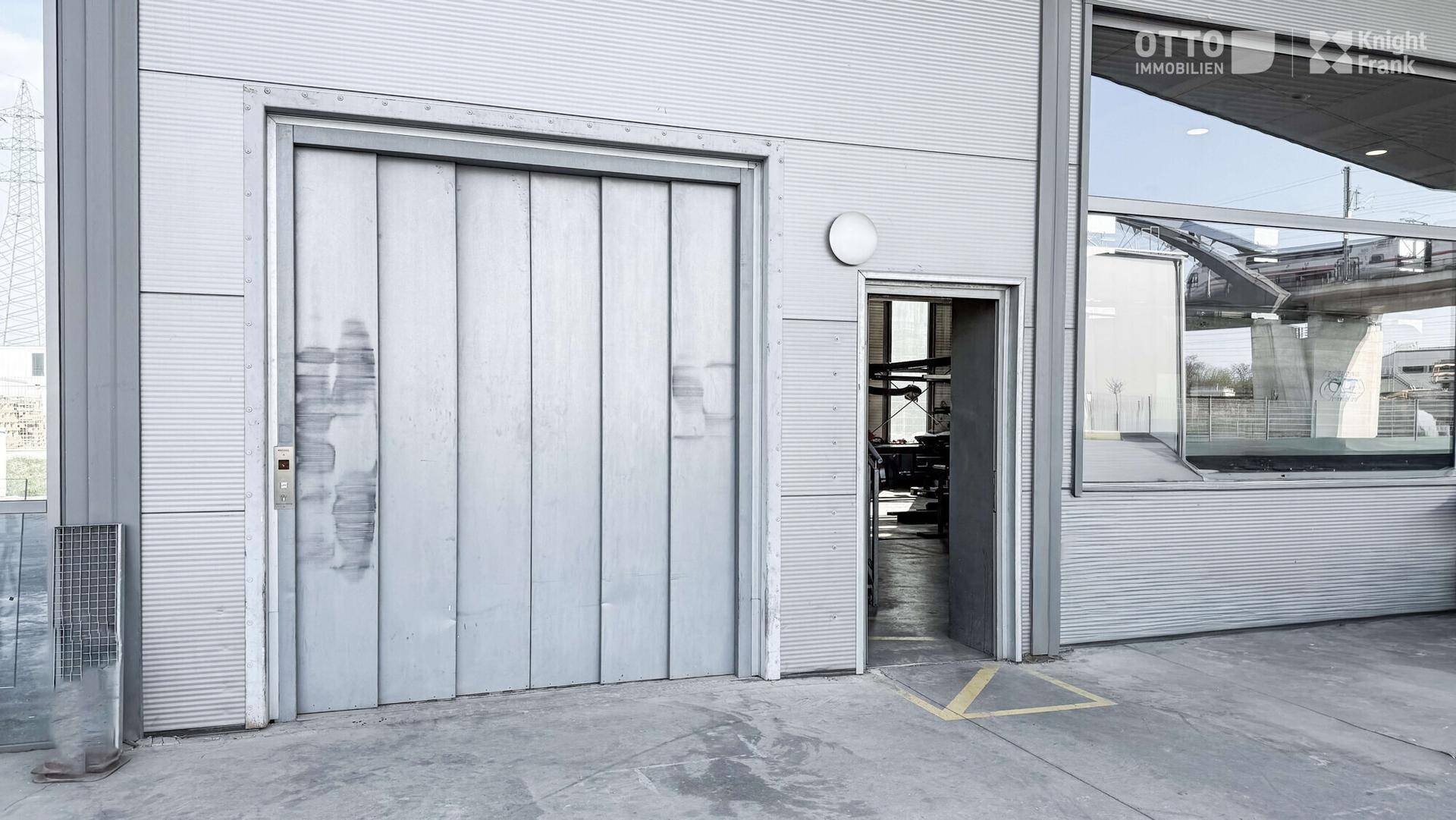 Außenansicht eines Industriegebäudes mit großem Lastenaufzug und separatem Eingangsbereich.