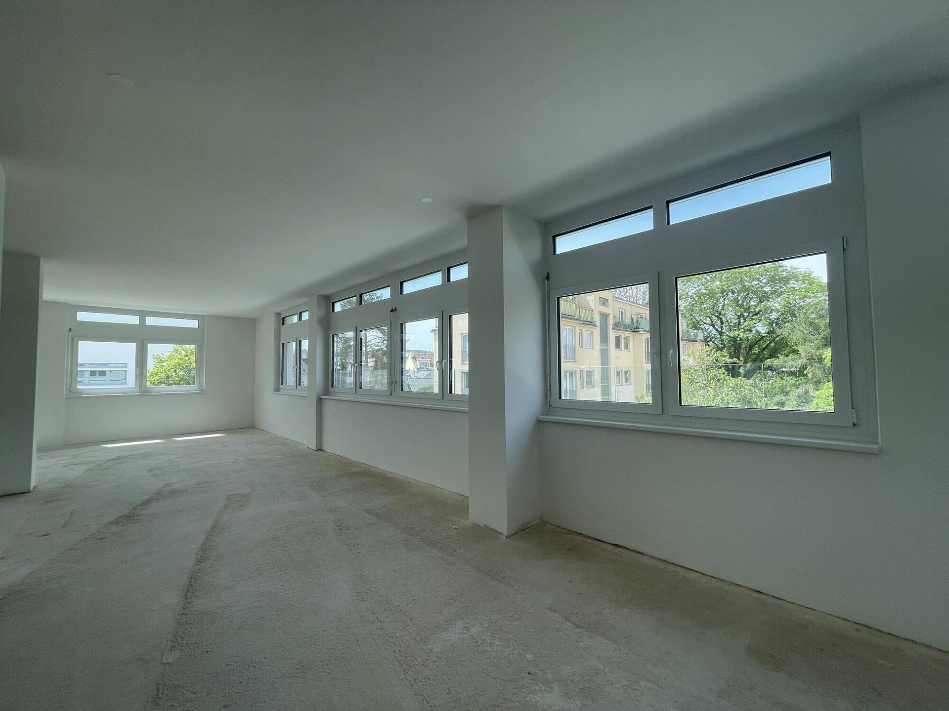 Geräumiger Bürobereich mit vielen Fenstern und Blick ins Grüne, ideal für eine ruhige Arbeitsumgebung.