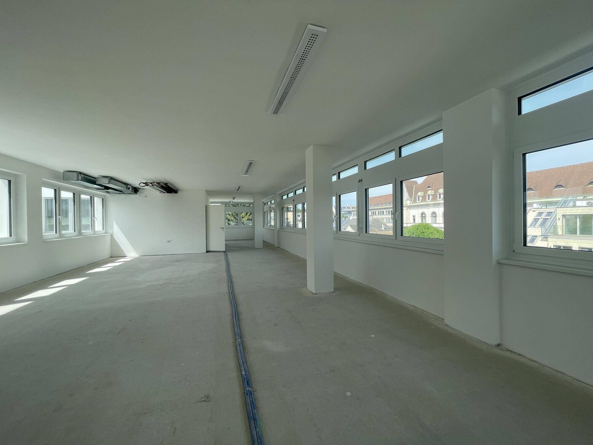 Weitläufiger Bürobereich mit durchgehenden Fensterfronten und einem offenen Grundriss, der viel Flexibilität bietet.
