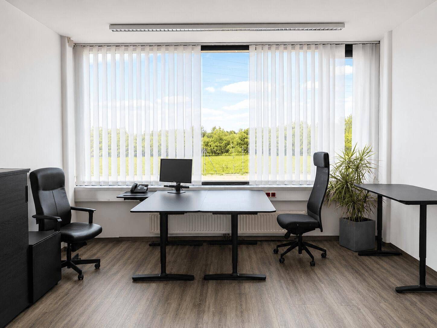 Helles Büro mit modernem Schreibtisch, Bürostuhl und vertikalen Jalousien am Fenster.