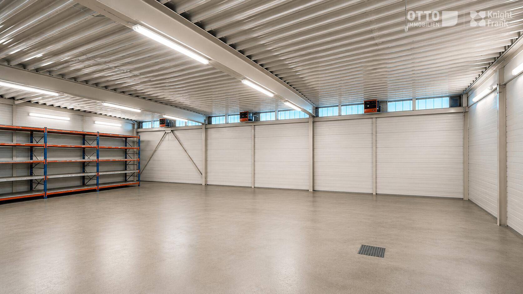 Leerer Lagerraum mit hohen Decken, Betonboden und natürlichem Lichteinfall.