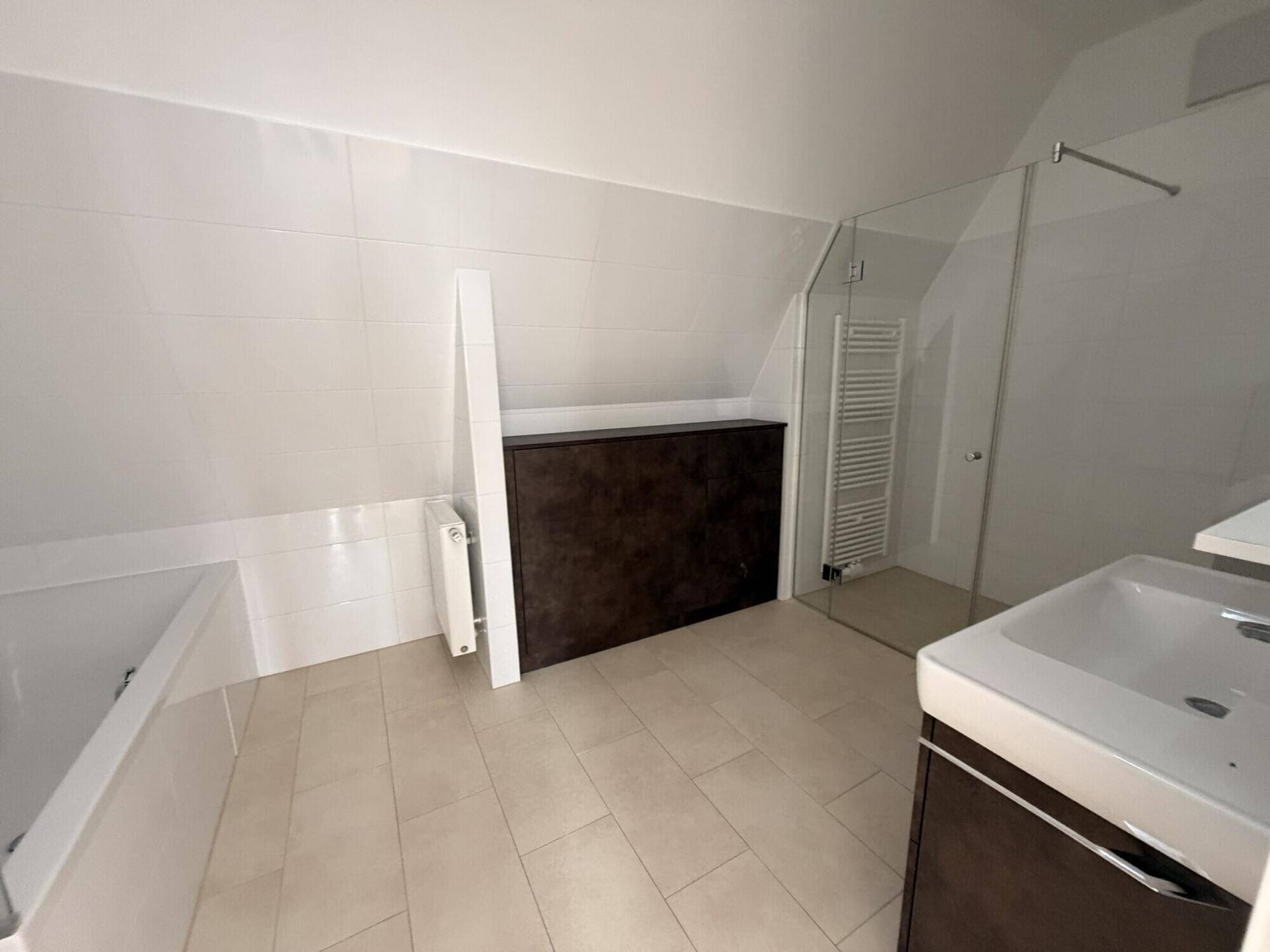 Modernes Badezimmer mit weißen Fliesen, begehbarer Dusche, Badewanne und Waschtisch unter einer Dachschräge.