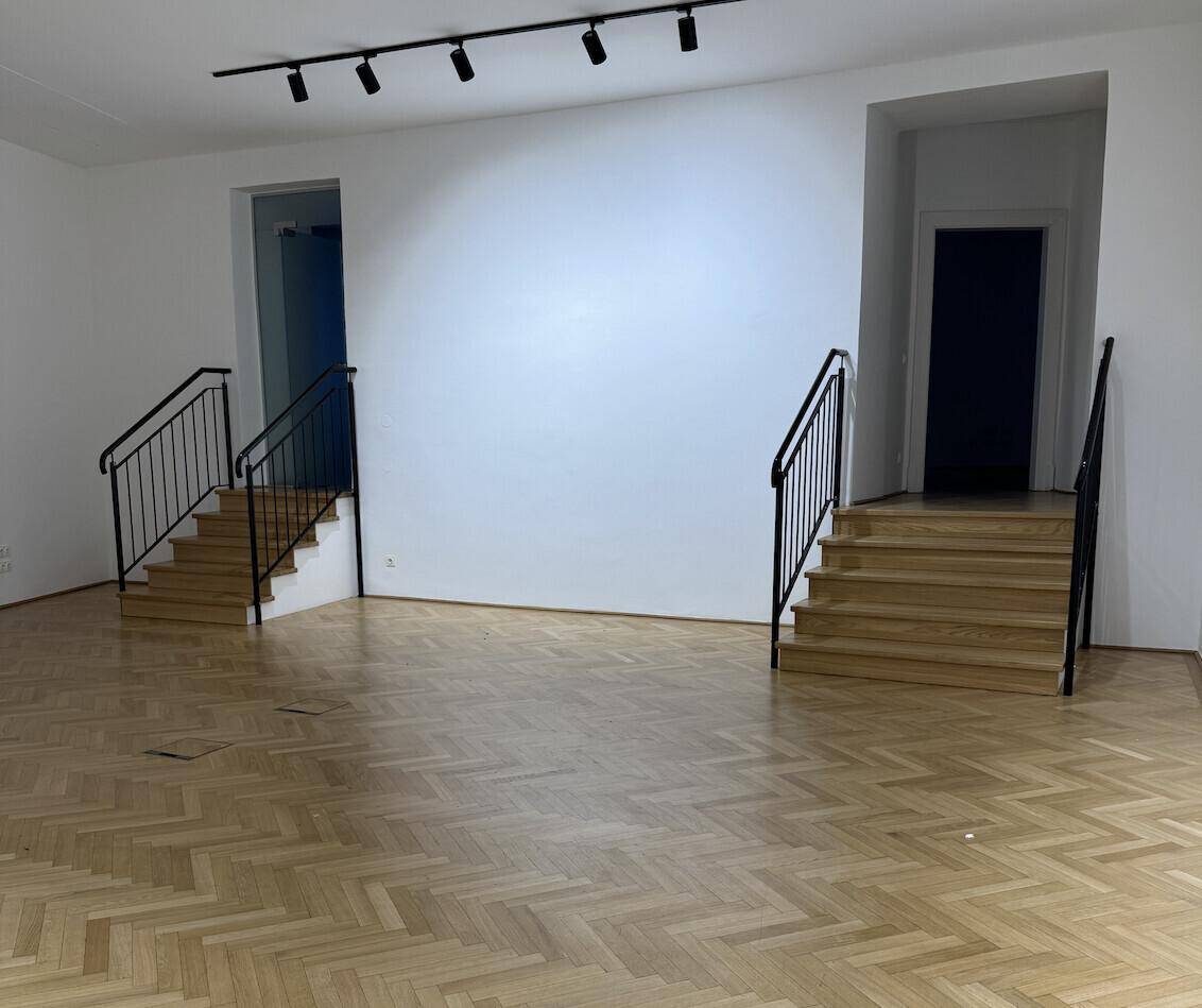 Heller Flur mit zwei Treppenaufgängen und Fischgrätparkett, bereit für individuelle Gestaltung und Nutzung.