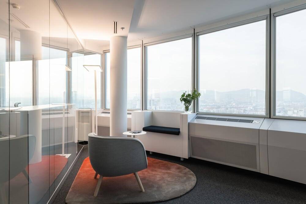 Moderner Loungebereich mit bequemen Sesseln, Teppich und weitem Blick durch die Fenster.