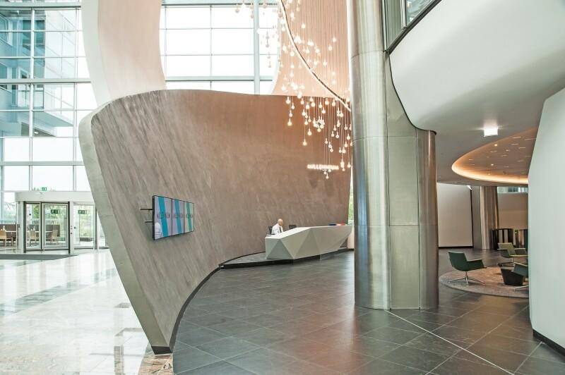 Elegante, moderne Lobby mit geschwungenen Wänden, dunklem Fliesenboden und stilvoller Beleuchtung.