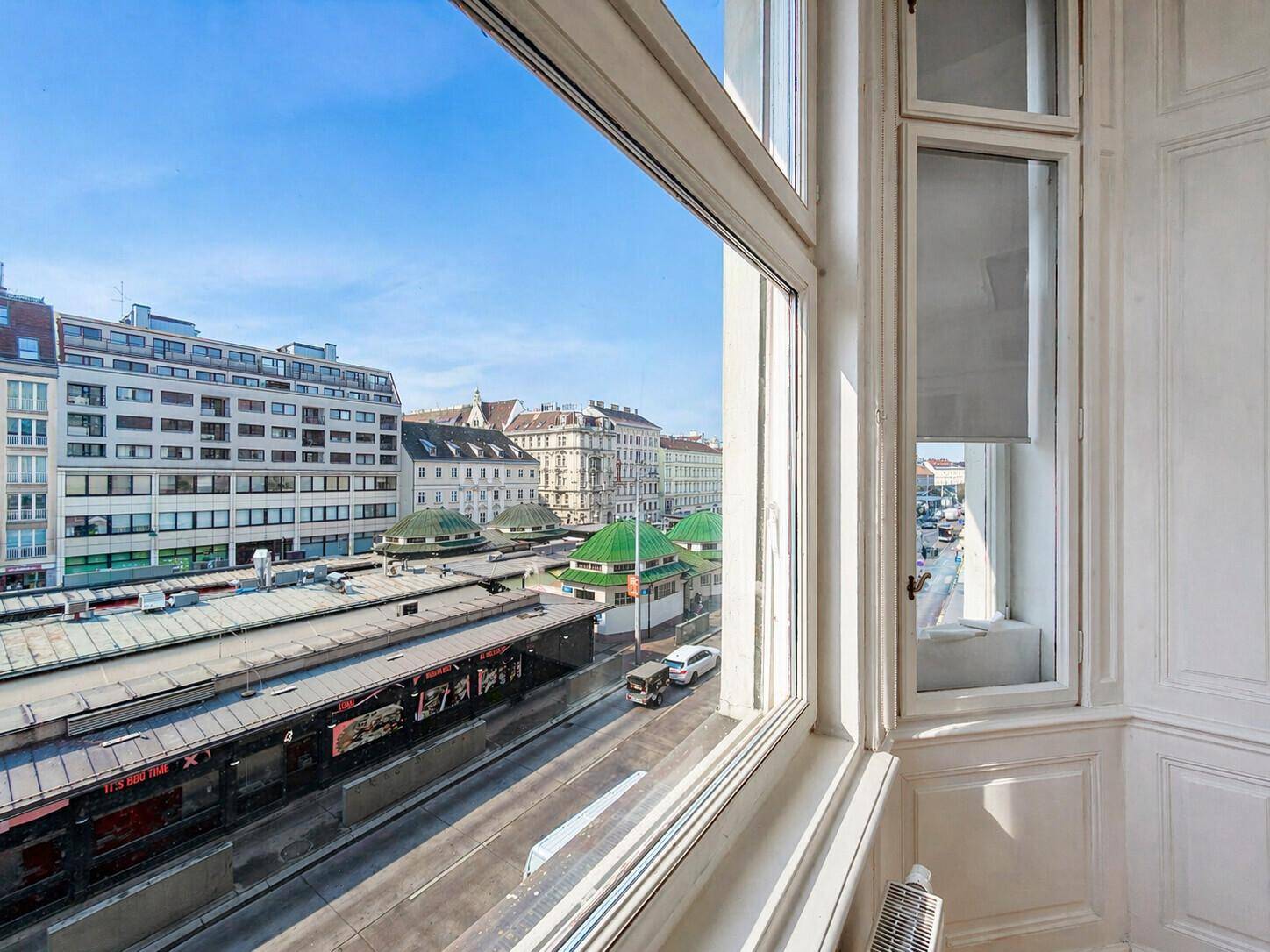 Blick aus einem großen Fenster auf eine belebte Stadtstraße mit Gebäuden und Verkehr.