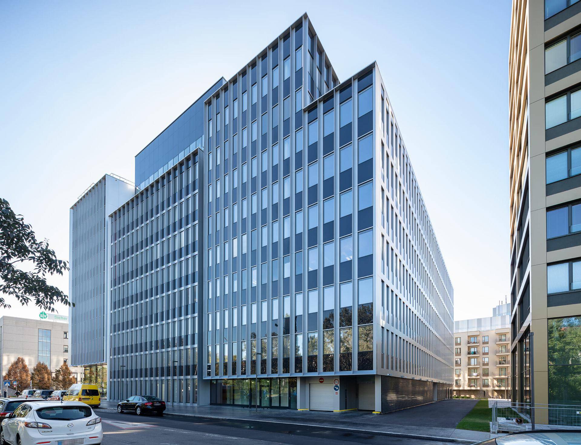 Modernes Bürogebäude mit einer eleganten Glasfassade und klaren architektonischen Linien an einem sonnigen Tag.