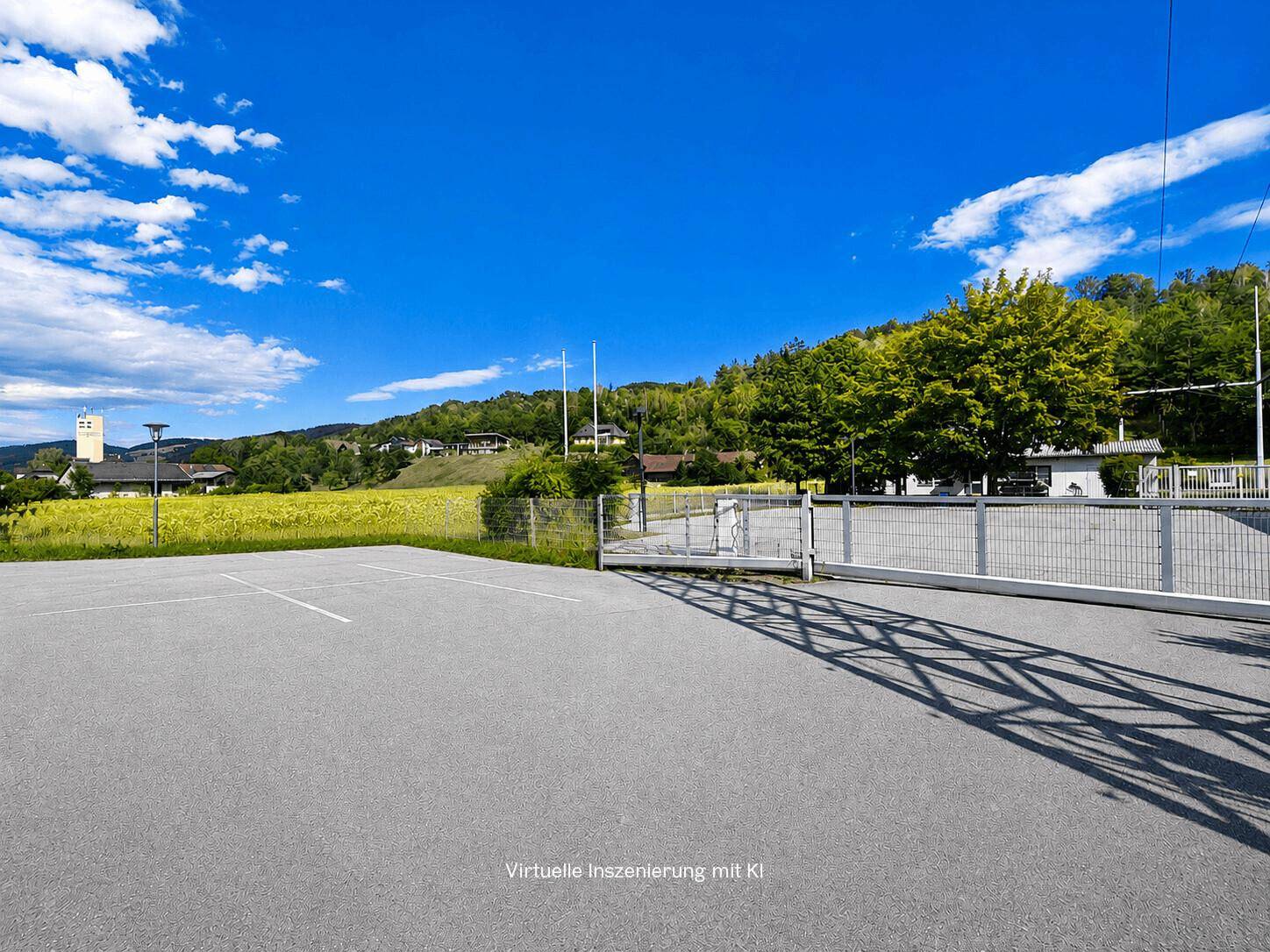 Großer asphaltierter Parkplatz mit Schiebetor und weitem Blick auf die grüne Landschaft.