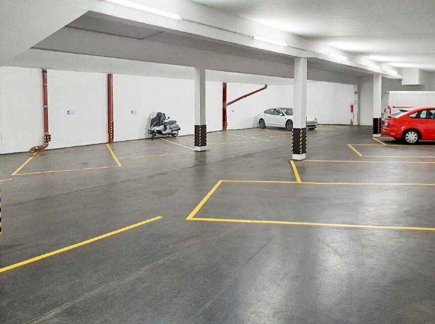 Geräumige Tiefgarage mit markierten Parkplätzen und einigen Fahrzeugen.
