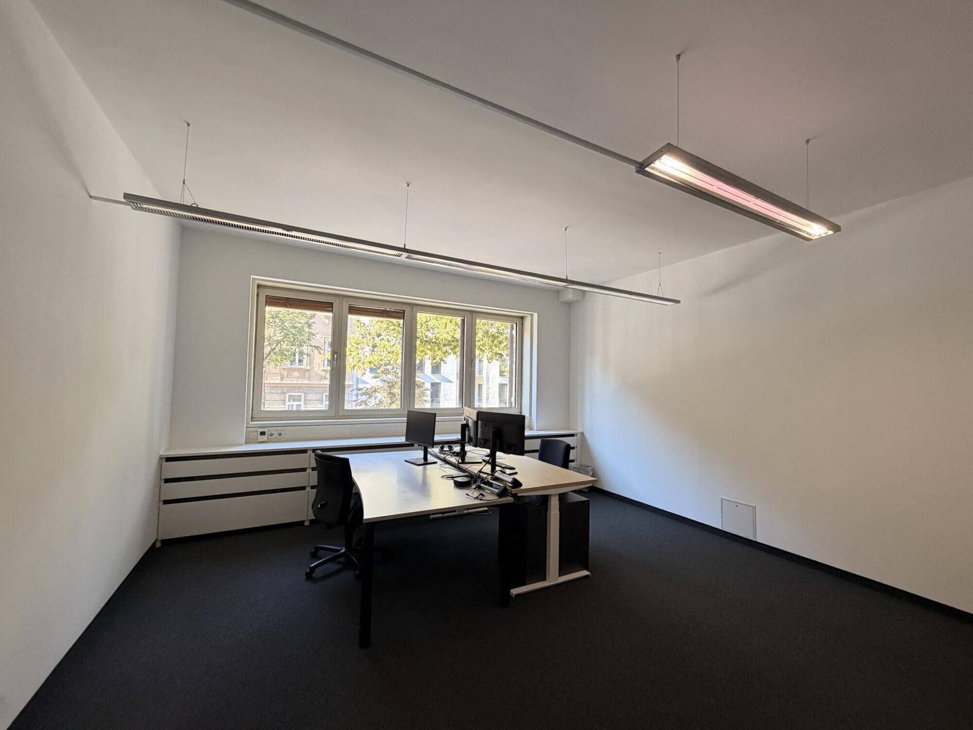 Helles Büro mit modernem Schreibtisch, Computern und Blick auf die Umgebung durch das Fenster.