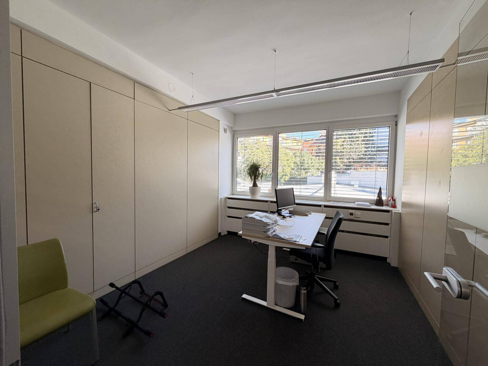 Funktionales Büro mit Schreibtisch, Bürostuhl und praktischen Einbauschränken entlang der Wände.