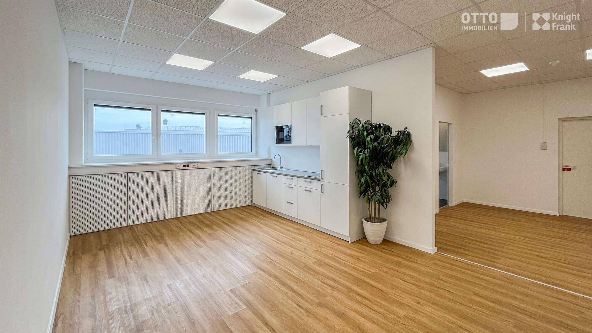 Funktionale Teeküche in einem hellen Büroraum mit Fenster und Stauraum.