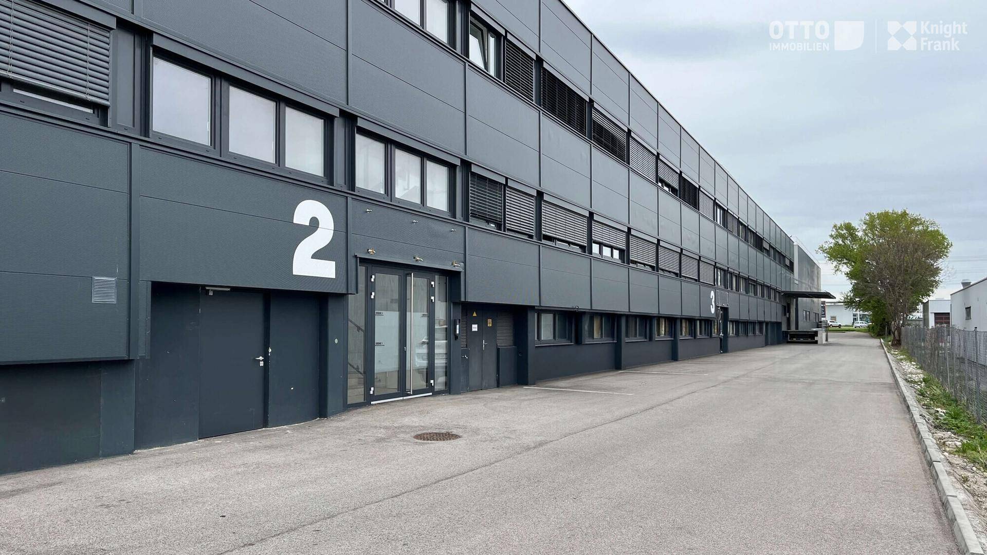 Moderne Gewerbeimmobilie mit dunkler Fassade und zahlreichen Fenstern, gut gepflegt.